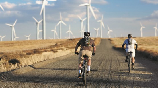 2 men cycling by some wind turbines