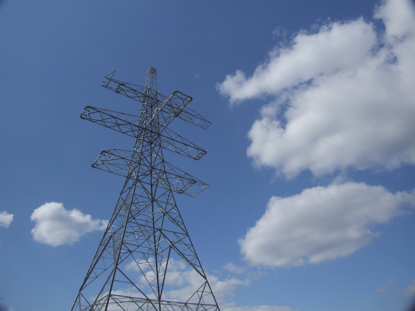 A high angle view of an electricity pylon against a blue and cloudy sky 
