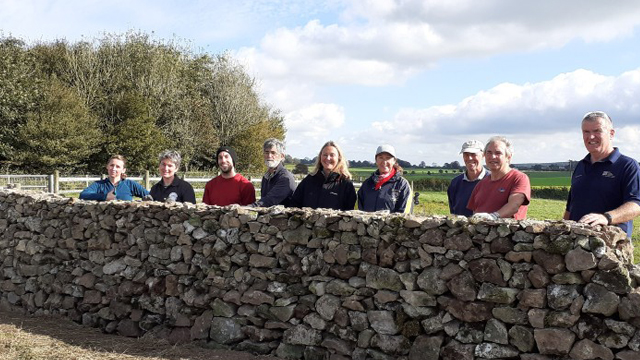 Group of people behind a dry stone wall