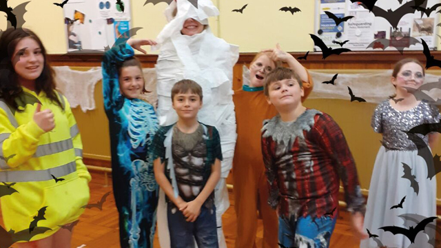 Children dressed in Halloween outfits with superimposed bats in the foreground