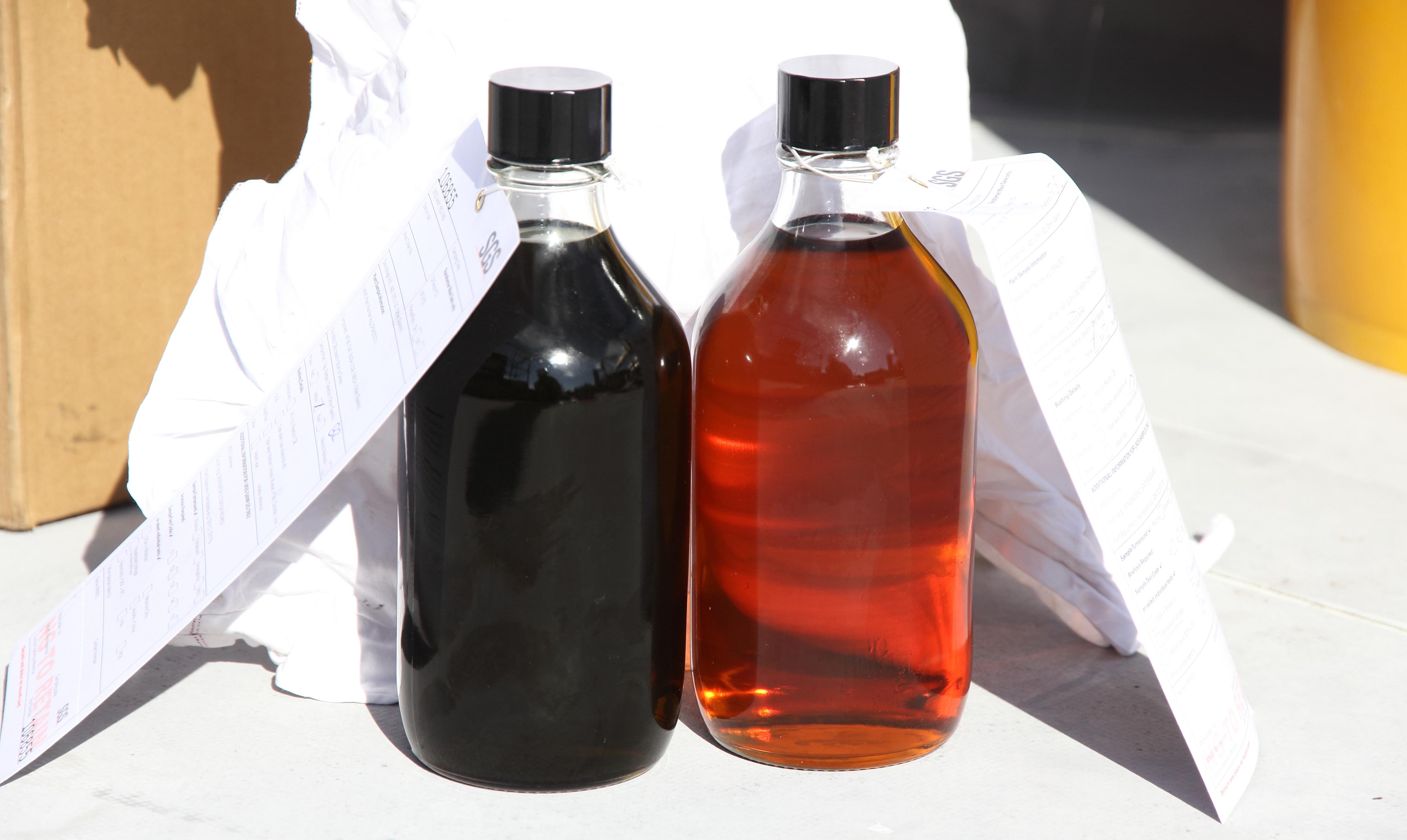 Two glass bottles, one with dirty and one with clean oil
