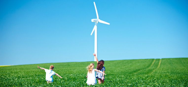 Children in a field with wind turbines