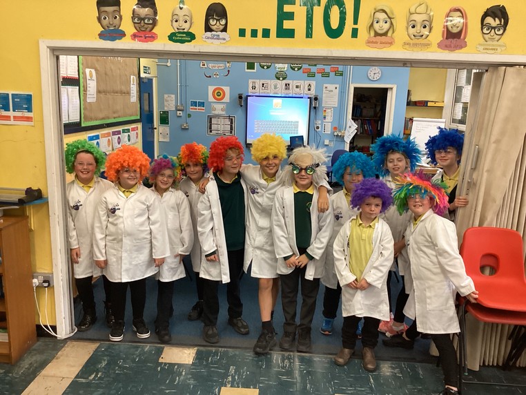 A group of children at a primary school in Wales dressed up in white lab coats and colourful wigs.