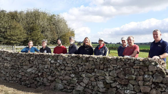 Group of people behind a dry stone wall