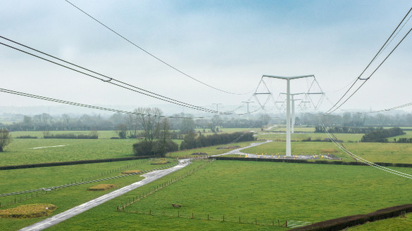 New electricity T-pylons with overhead lines across green fields