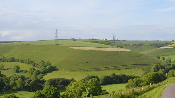 A bird's eye view of a Dorset hillside with electricity pylons in shot 