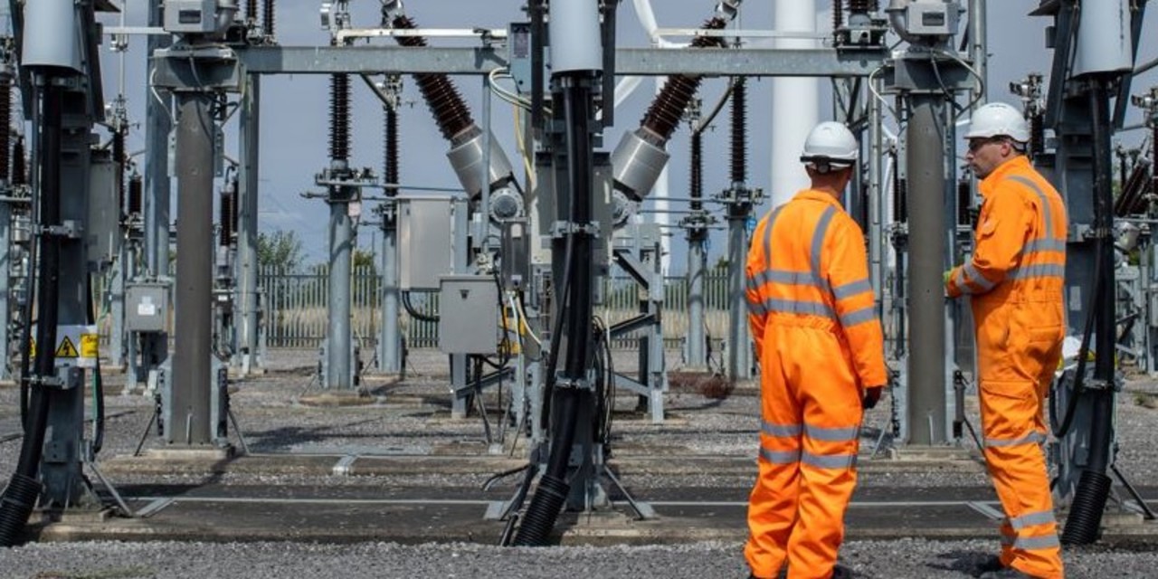 Two engineers wearing orange high-vis overalls and hard hats at Bicker Fenn Substation