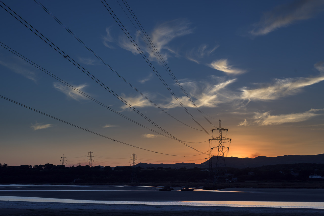 Electricity transmission pylons and overhead lines over the Dwyryd Estuary in Wales at sunset