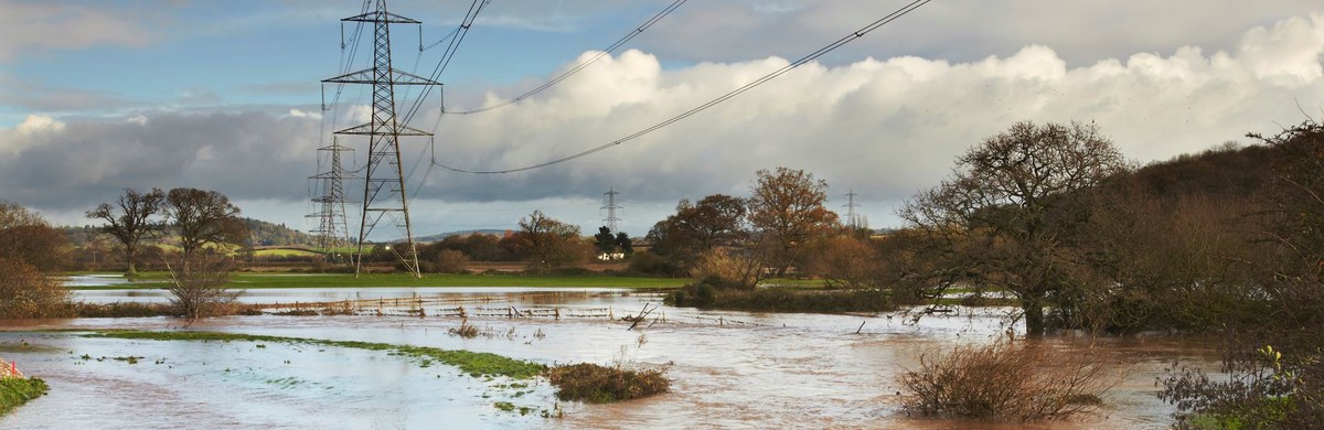 Electricity transmission pylons and overhead lines across a flooded countryside