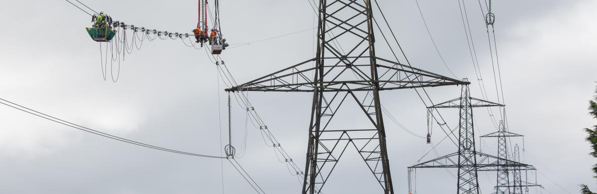 A row of electricity pylons with National Grid workers inspecting the overhead cables - Walham to Cilfynydd