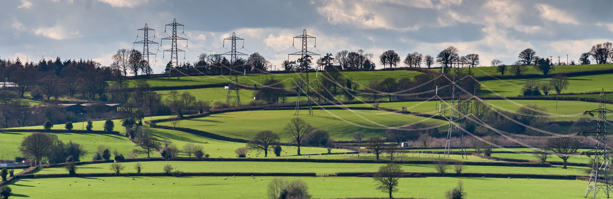 High-voltage power lines and pylons in green fields