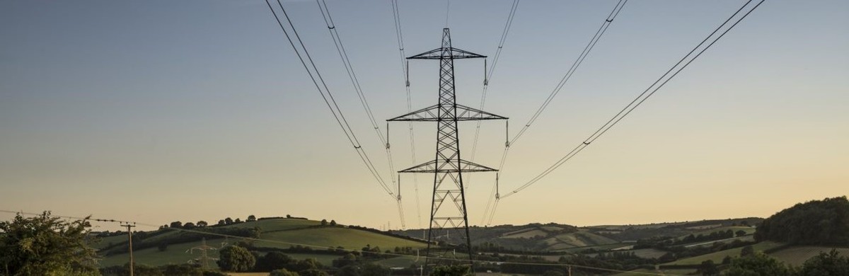National Grid partners with Met Office to boost capacity on the electricity transmission network - electricity transmission pylon and overhead lines at dusk