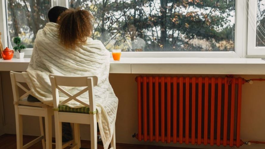 Person sitting near window with radiator heater