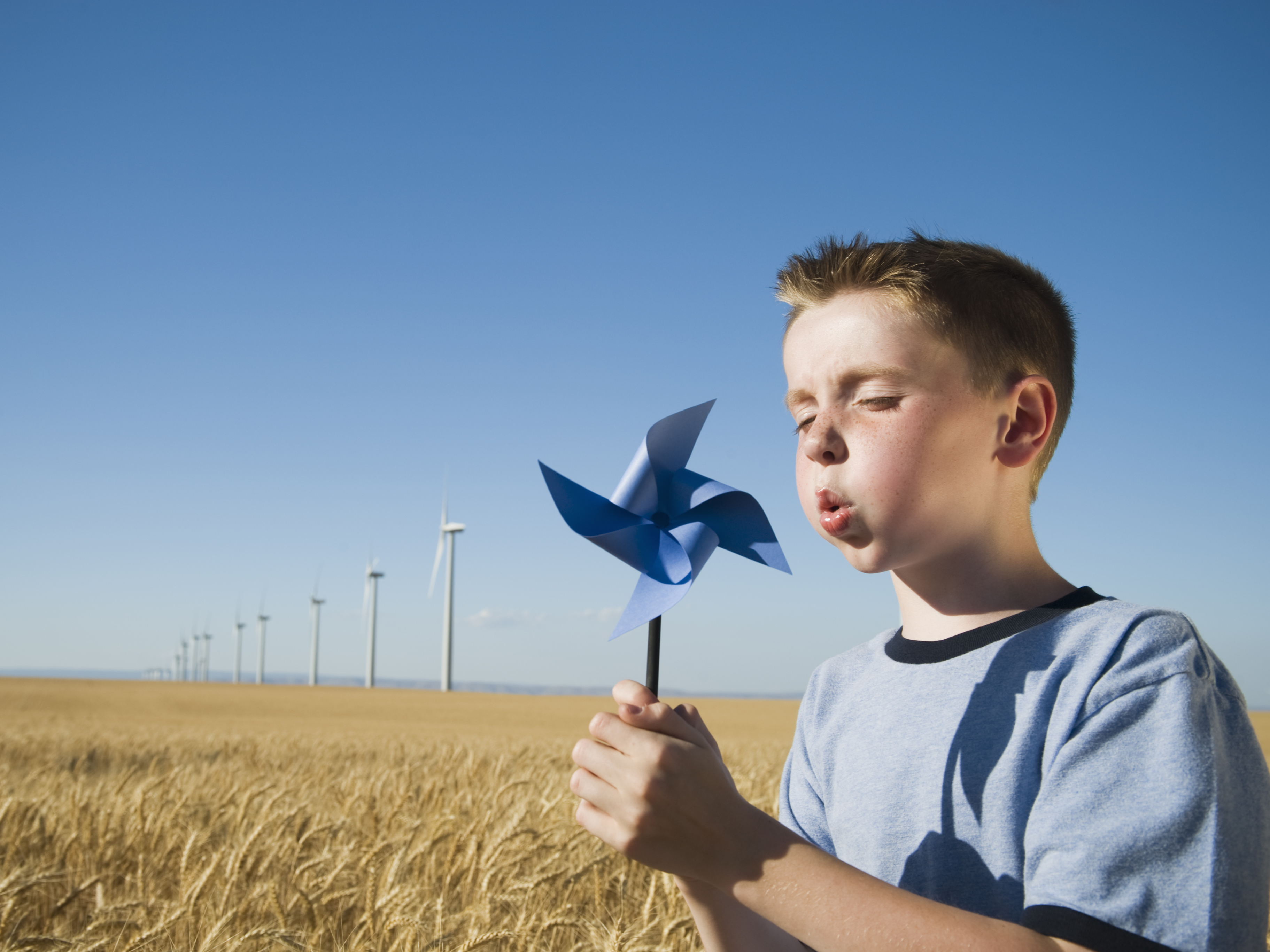 Boy blowing a windmill in a field