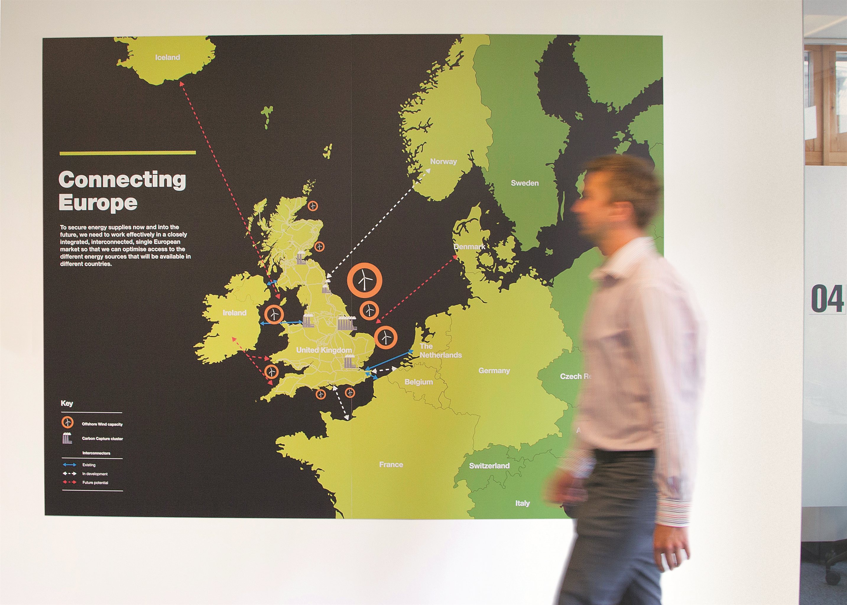 Connecting Europe map on a white wall with someone walking in front of it