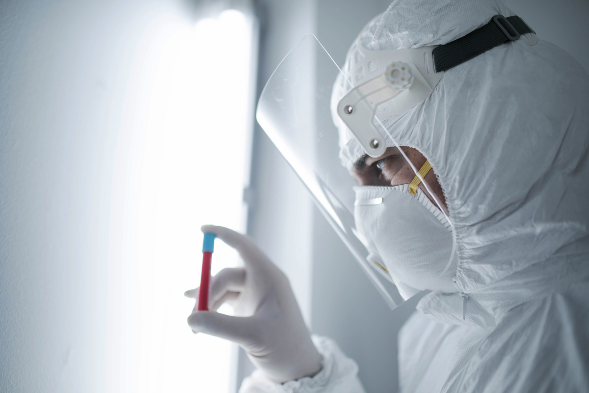 Person wearing full PPE holding blood vial used for National Grid 'Backing the quest for a COVID-19 vaccine' story