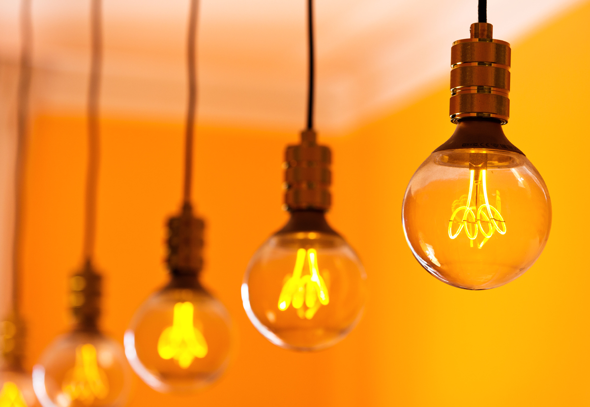 Row of lightbulbs hanging in a room with orange walls - used for the National Grid story 'Britain’s electricity explained: new monthly report shows how we use power'