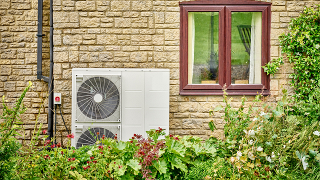 Electric heat pump on a yellow brick building by a window