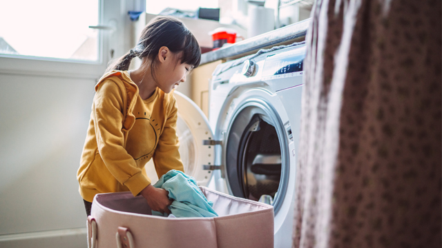 Young girl loading a washing machine
