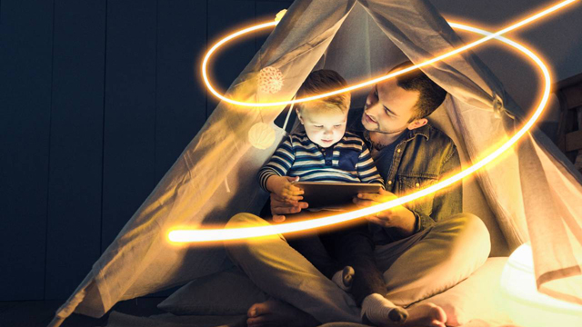 Father and son sitting in a tipi looking at a tablet