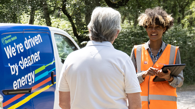 We're driven by cleaner energy - woman with clipboard talking to a man next to an electric van
