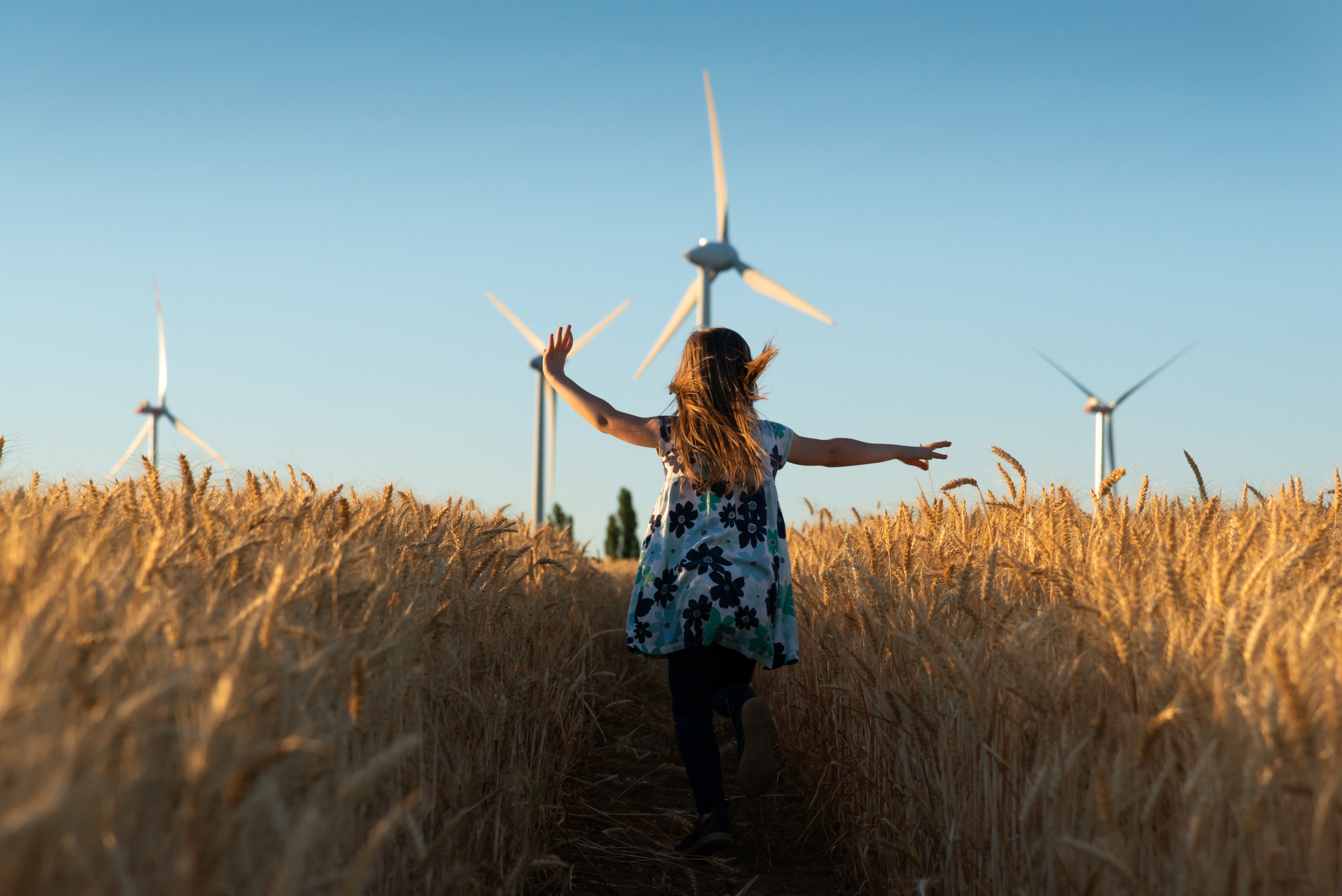 Responsibility - girl running in field with wind turbines in the background