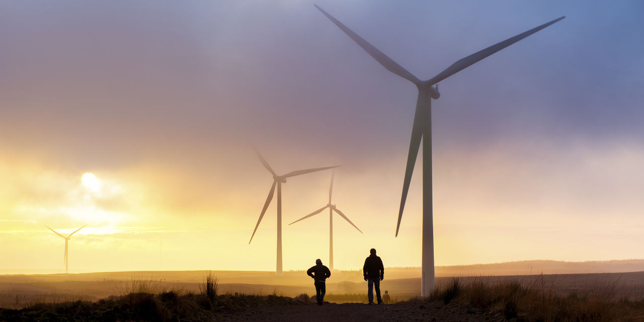 People walking across fields next to wind turbines - used for the National Grid story '200MW Crocker Wind Farm brings cleaner power online'