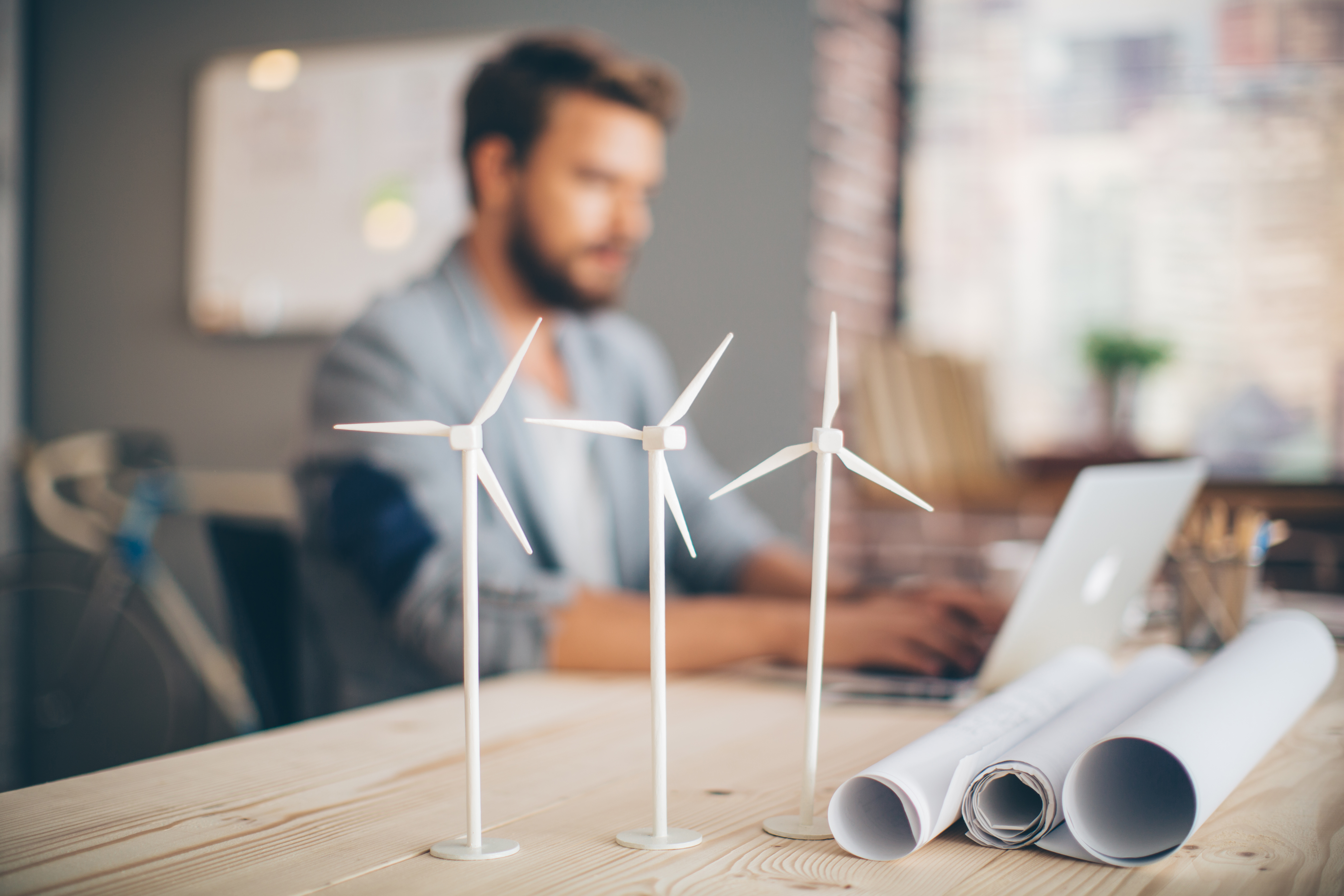 Man works alongside model of windfarm and plans for work