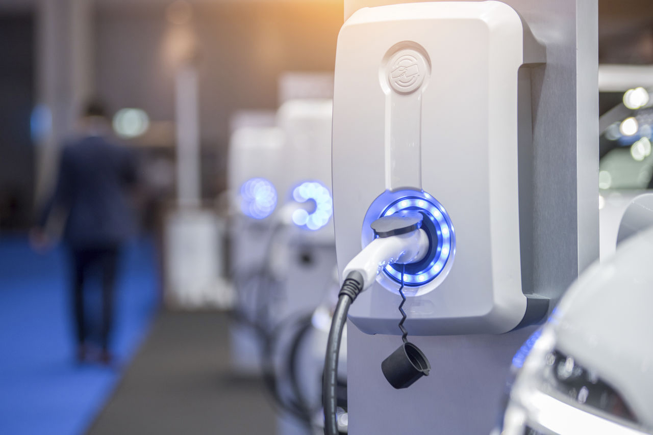 Electric vehicle charging point in garage with man walking away in background - used for the National Grid article 'Smart ways to shift the journey towards EVs for everyone into the fast lane'