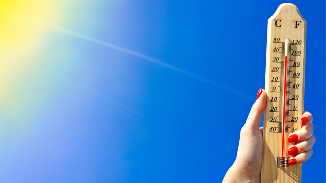 Hand holding thermometer showing high temperatures in the sun