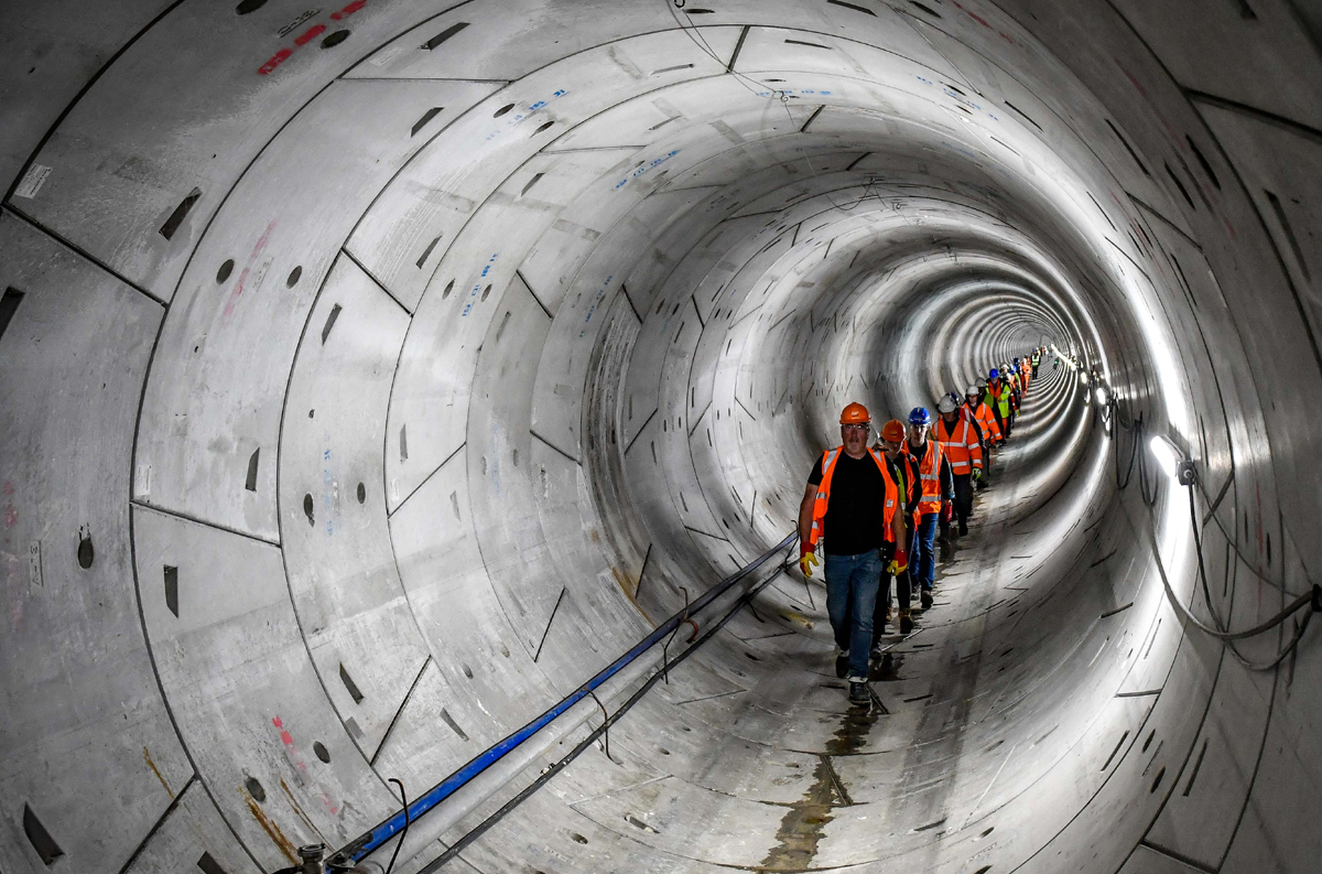 A line of people wearing hard hats and high-vis walking through the Humber Tunnel - used for the National Grid story 'Celebrating the completion of the Humber Tunnel'