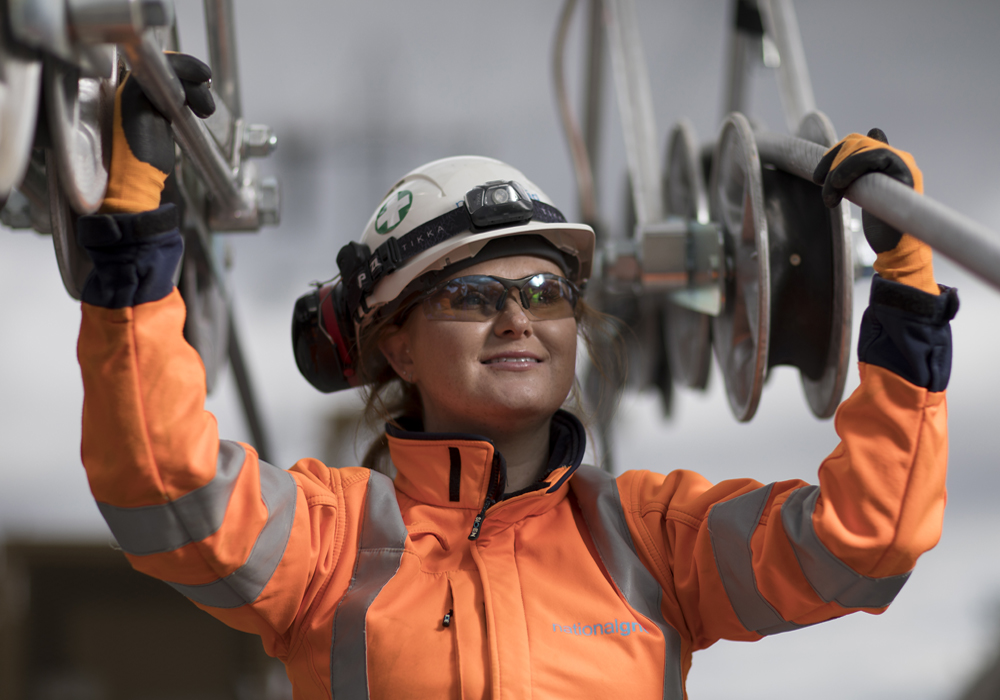 Female engineer wearing PPE holding National Grid high-voltage power cables