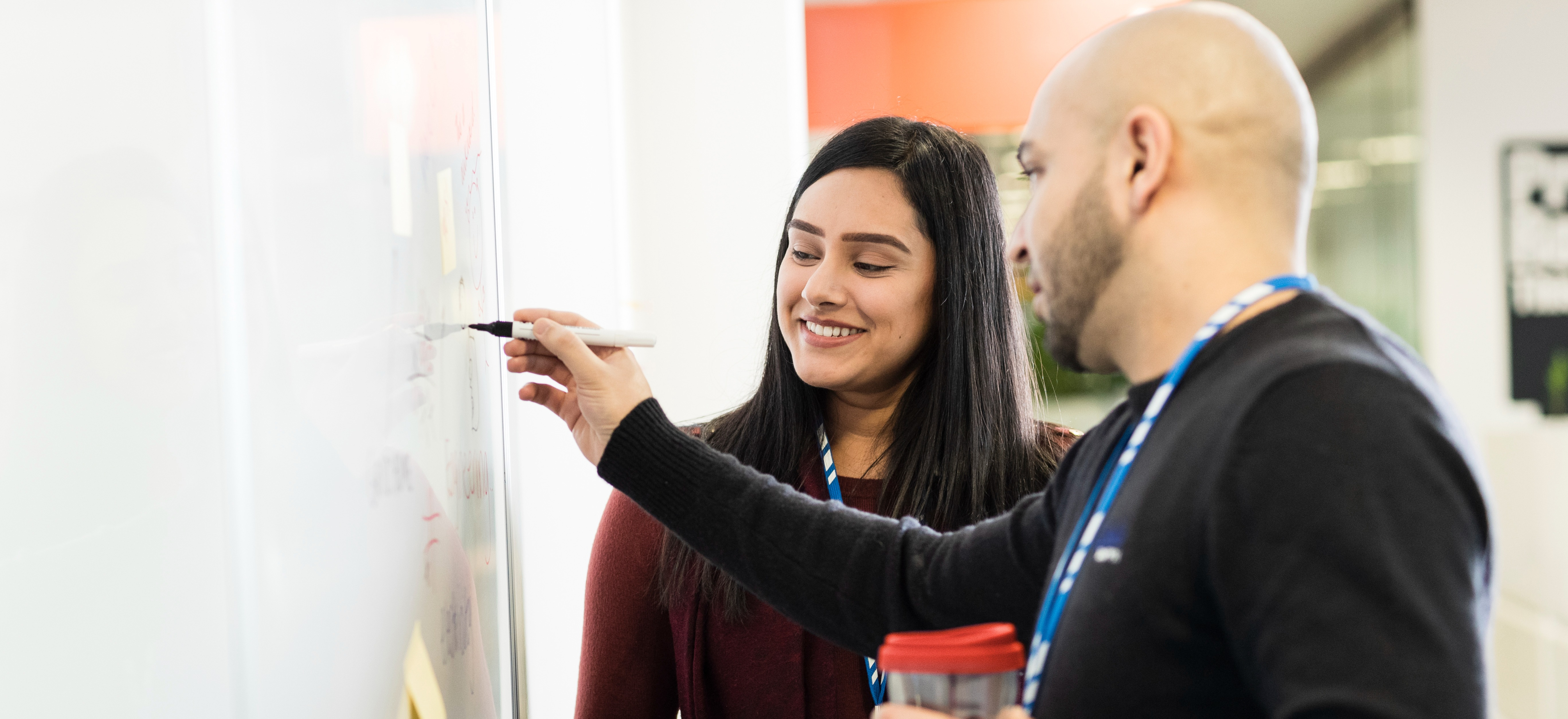 Two people writing on whiteboard
