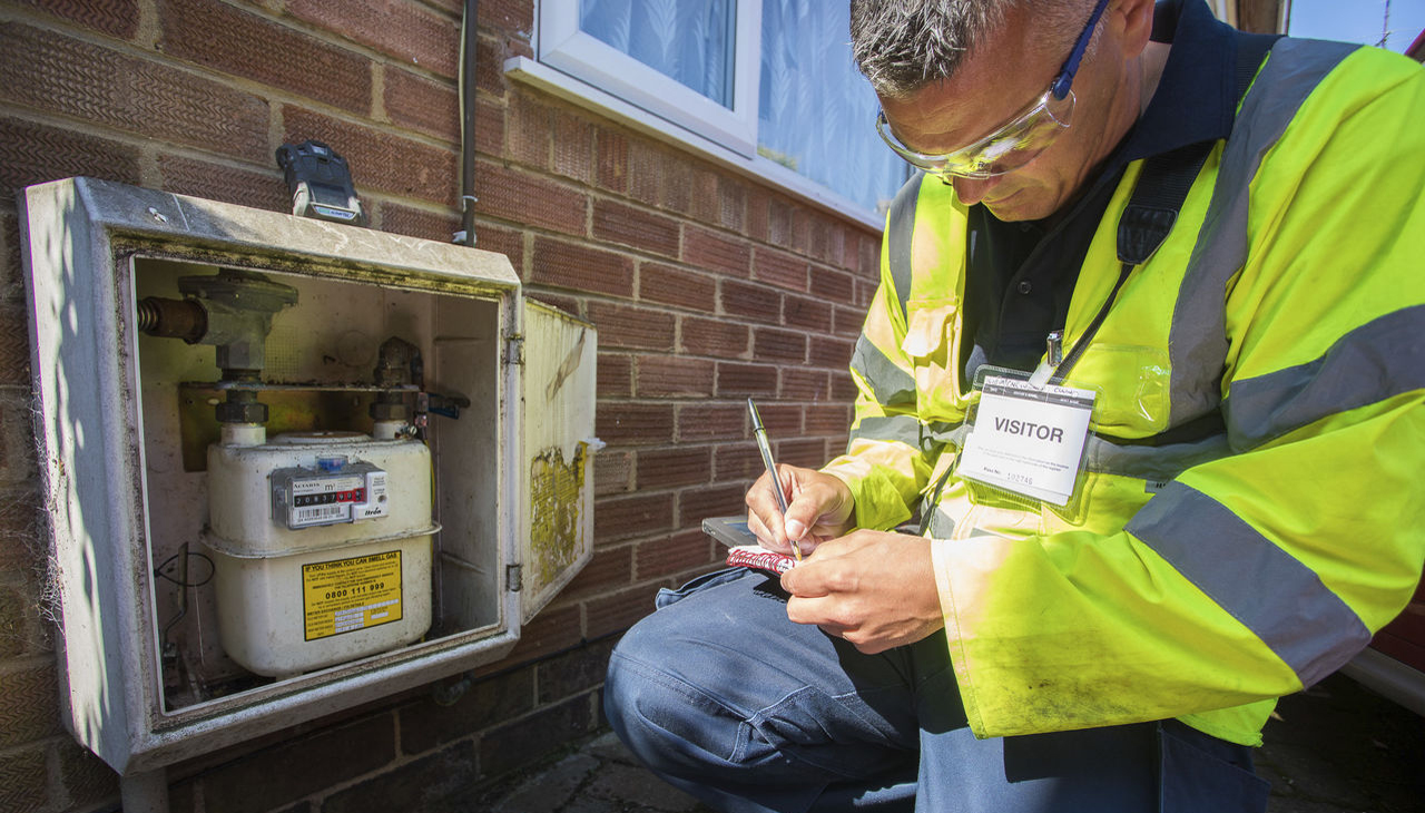 Metering engineer in high-vis jacket in front of gas meter - used for the National Grid story 'Why meters matter in a time of crisis'