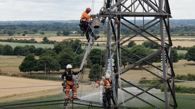 Engineers wearing PPE climbing up an electricity tower and along the overhead lines