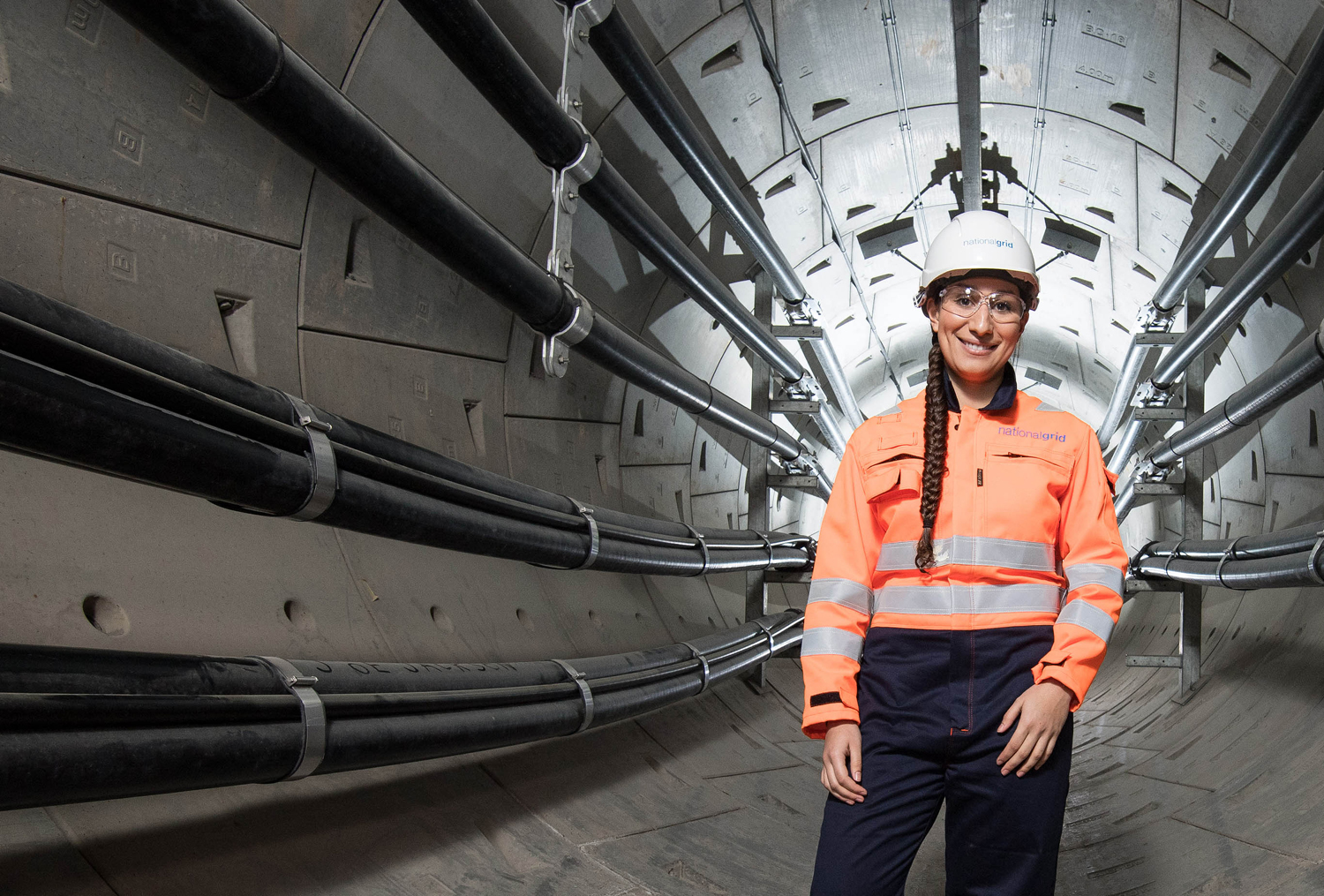 Female engineer wearing hard hat, safety goggles and overall inside London Power Tunnel - used for the National Grid story '400,000 new energy workers needed to power UK to net zero'