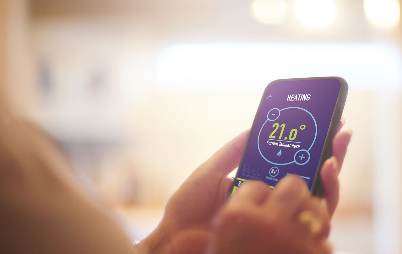 Hands holding a smart device showing heating and current temperature information - used for the National Grid story 'The future of home heating in a net zero UK'