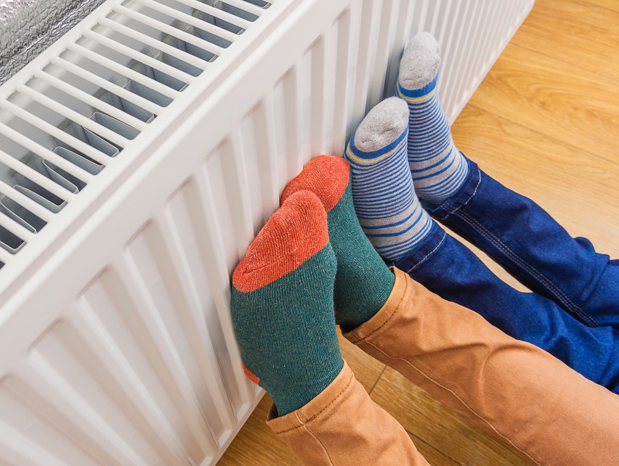 Two pairs of feet in colourful socks held against a radiator