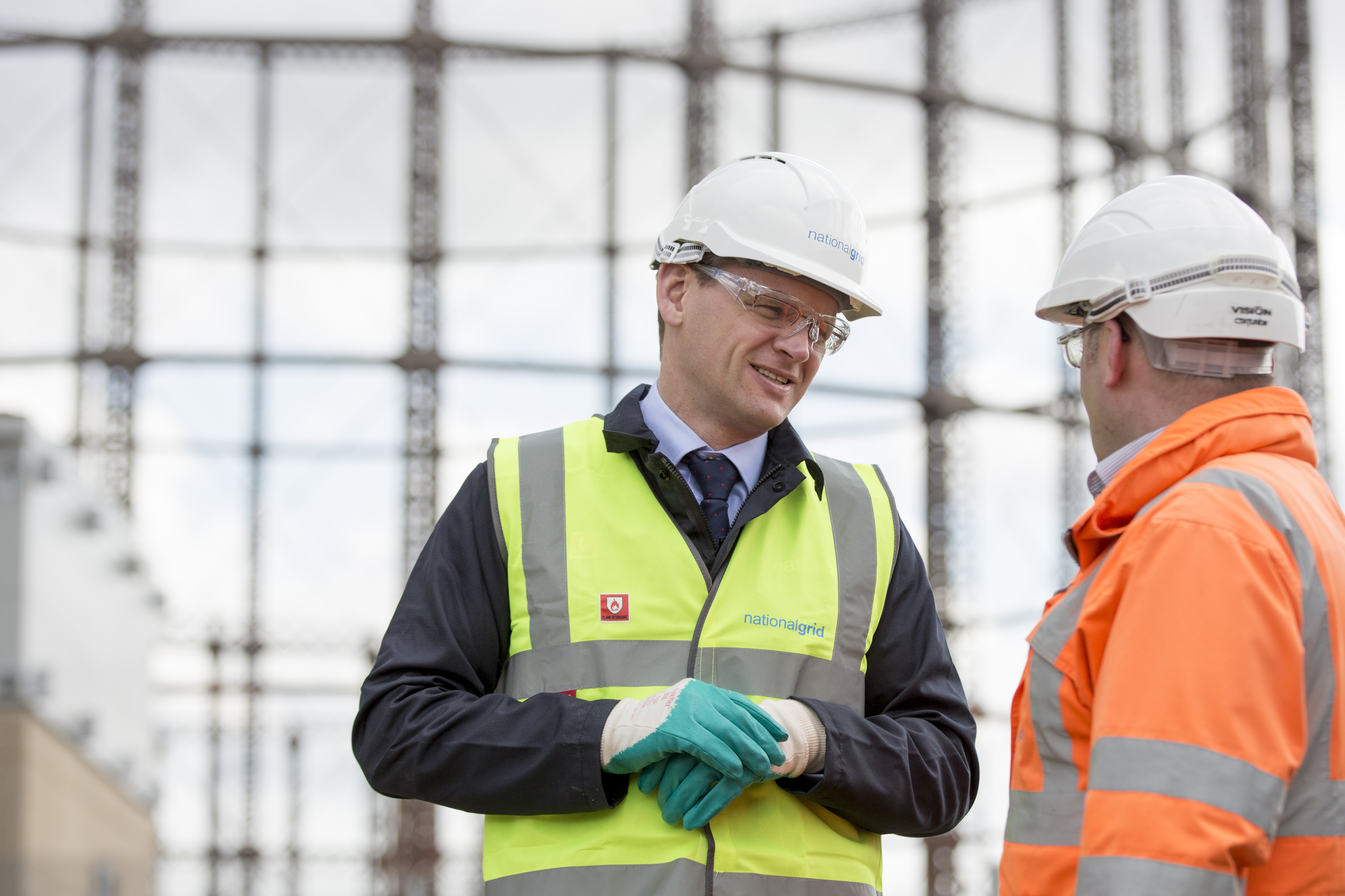 An image of National Grid CEO John Pettigrew and another man in safety gear in front of a gas holder