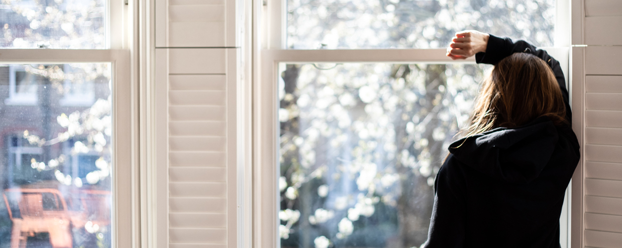 Woman looking through a window - social distancing - used for the National Grid story 'Caring for mental health during a crisis'