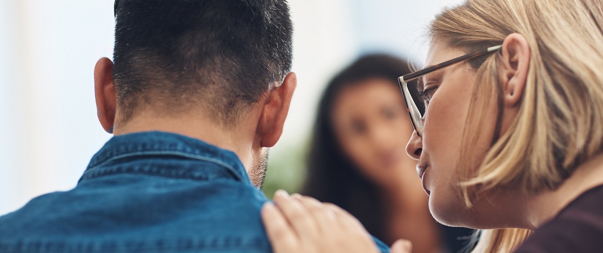 Woman talking to a man with her hand on his shoulder