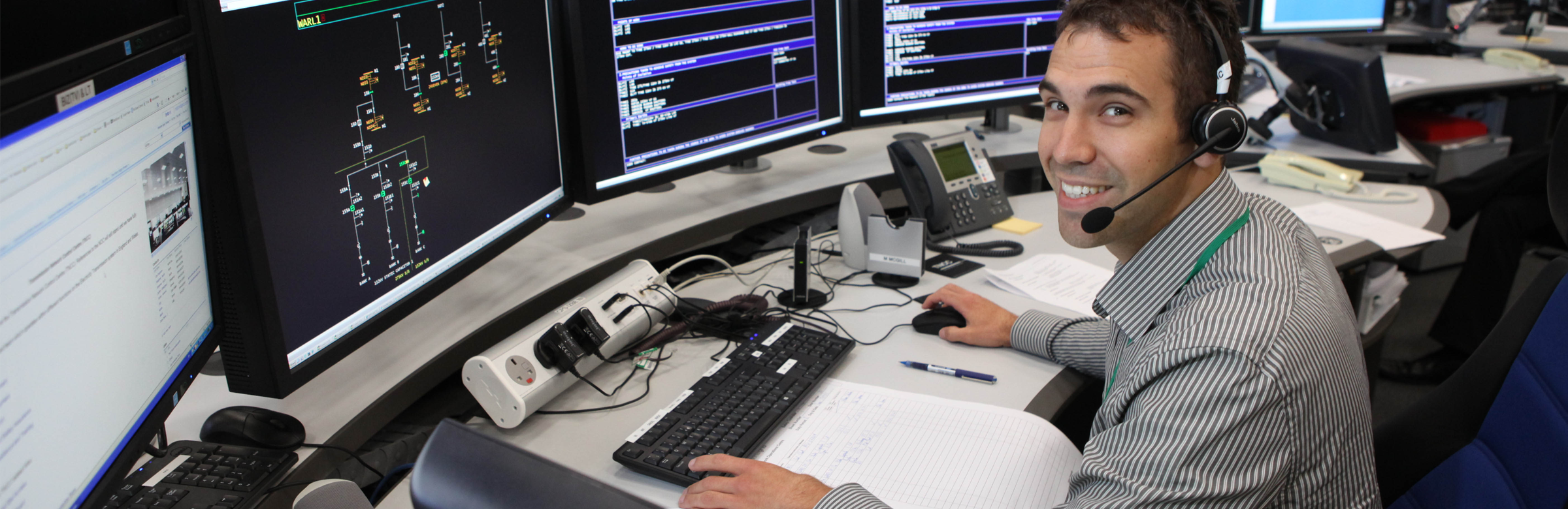 National Grid employee sitting in front of three computer screens inside an office - Contact Us