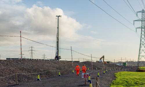 Two people walking down stone path near pylons