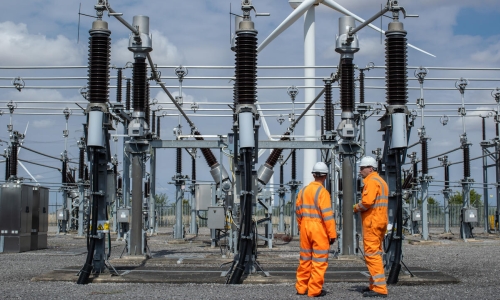 Two engineers wearing orange high-vis overalls and hard hats at Bicker Fenn Substation