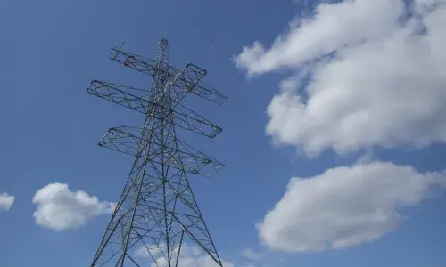 A high angle view of an electricity pylon against a blue and cloudy sky 