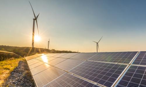 Solar panels and wind turbines at sunrise