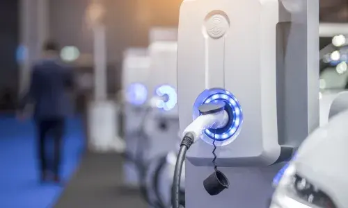 Electric vehicle charging point in garage with man walking away in background - used for the National Grid article 'Smart ways to shift the journey towards EVs for everyone into the fast lane'