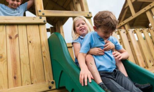 Young girl and boy sitting at the top of a slide