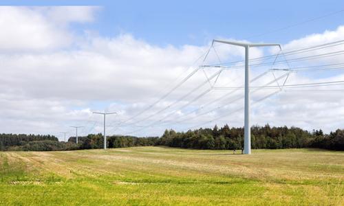New electricity T-pylons and overhead lines running across a field with woods in the background