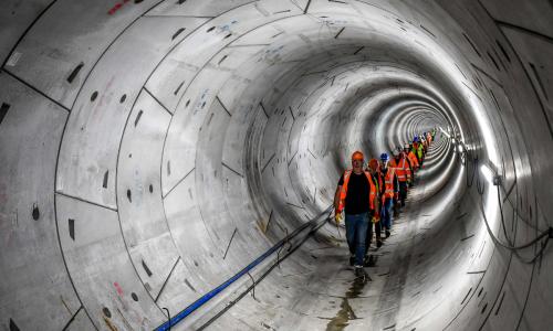 A line of people wearing hard hats and high-vis walking through the Humber Tunnel - used for the National Grid story 'Celebrating the completion of the Humber Tunnel'